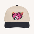 Beige cap with a pink and black Bomb face design on a white background